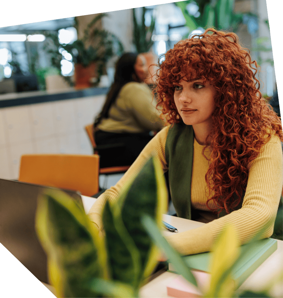 Curly-haired girl sitting behind laptop at office desk