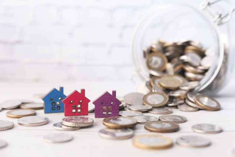 colorful-wooden-houses-and-coins-on-white-the-co-2024-12-13-09-49-34-utc