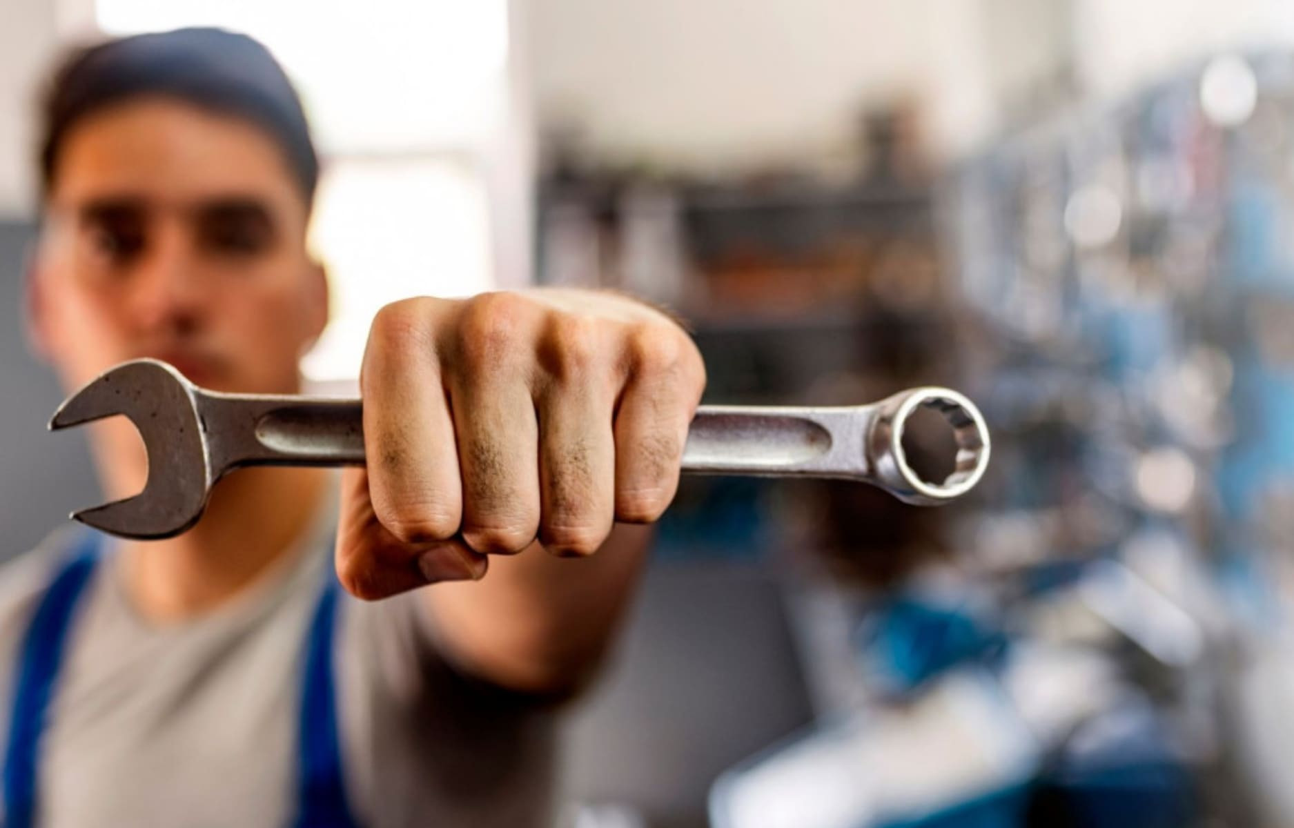 Man in overalls holding up wrench
